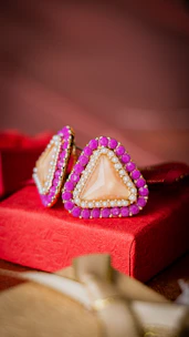 a pair of pink and white earrings sitting on top of a red box