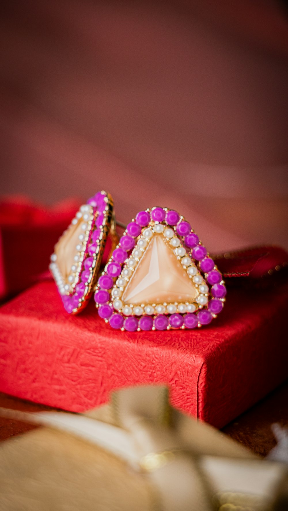 a pair of pink and white earrings sitting on top of a red box