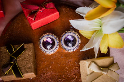 Elegant gold earrings with intricate designs displayed against a deep purple velvet background.