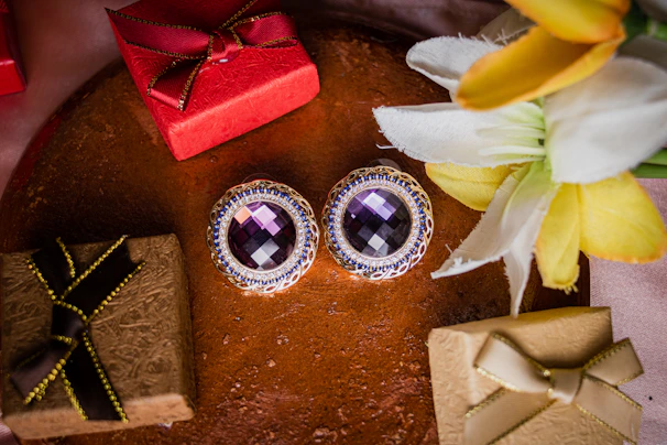 Elegant gold earrings with intricate detailing displayed against a deep purple velvet background.