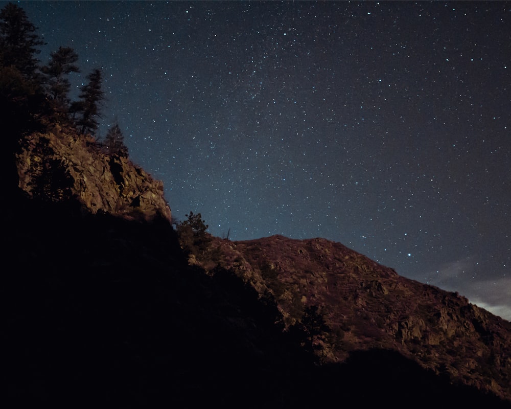 the night sky with stars above a mountain