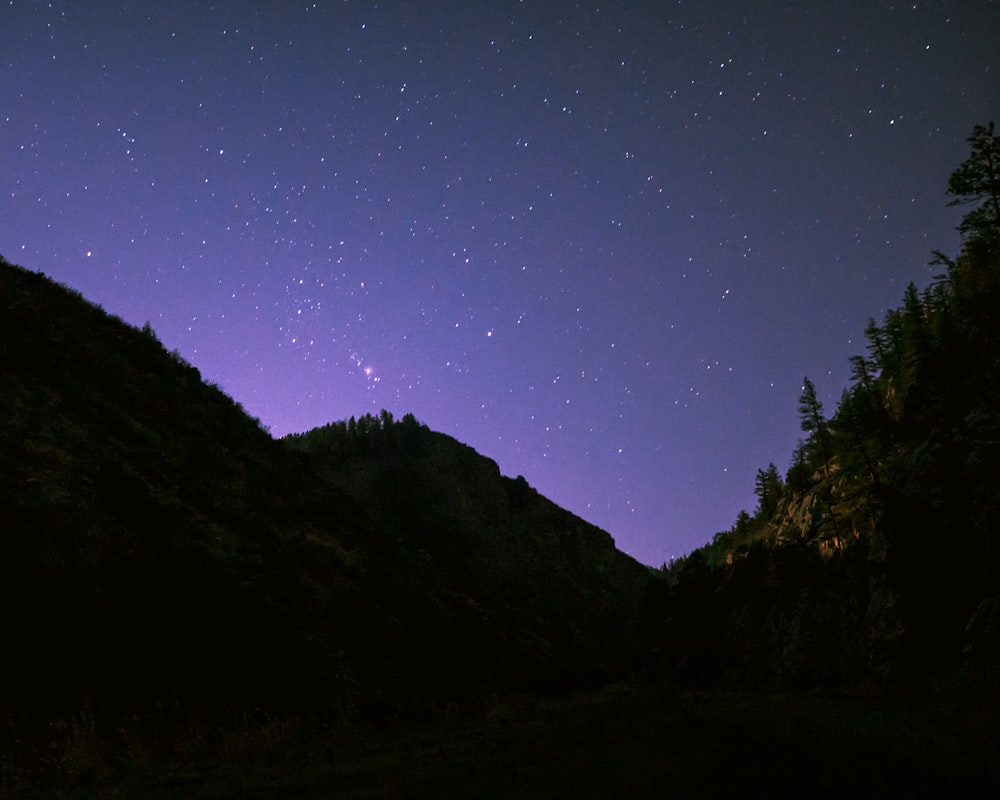 the night sky with stars above a mountain