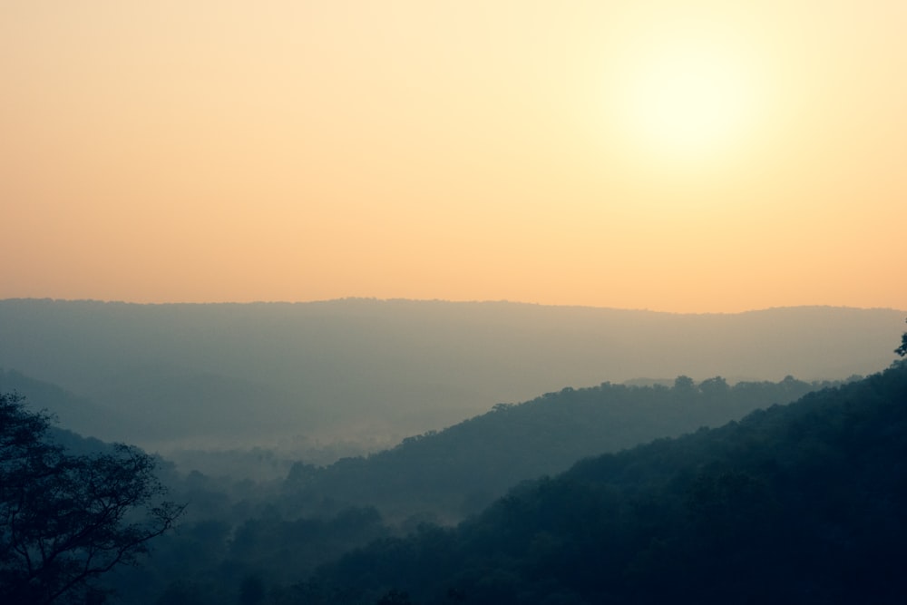 the sun is setting over the mountains in the distance