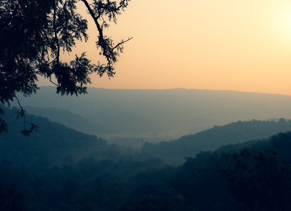 the sun is setting over the mountains in the distance