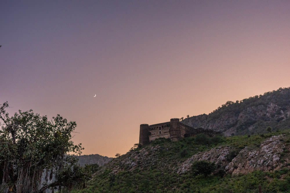 a castle on a hill with a moon in the sky