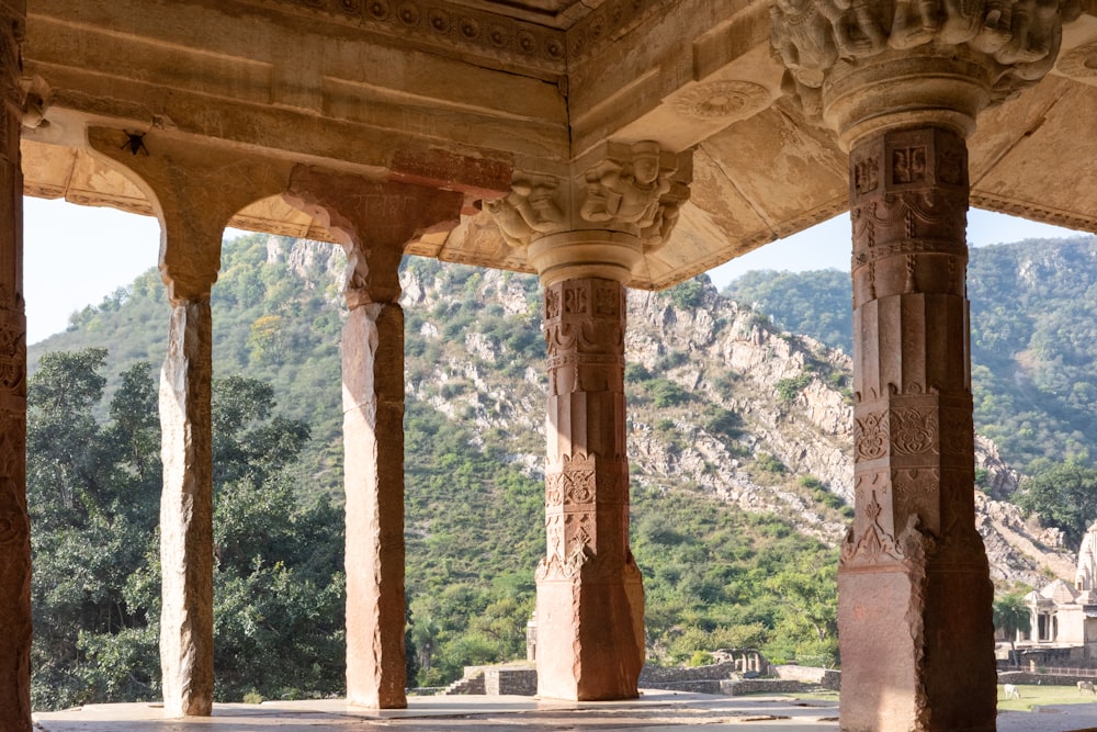 a stone building with columns and a mountain in the background