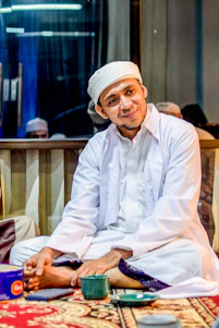 A Muslim man in modest business attire working thoughtfully at a sleek, modern workspace in Boston.