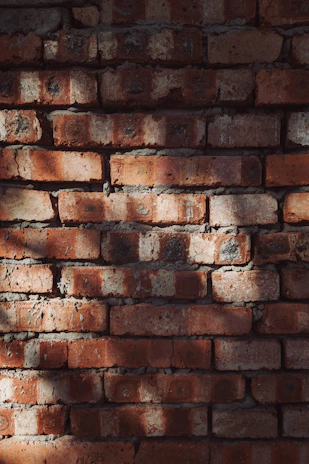 Close-up of warm, textured Spanish-style brickwork with intricate patterns under soft tropical sunlight.