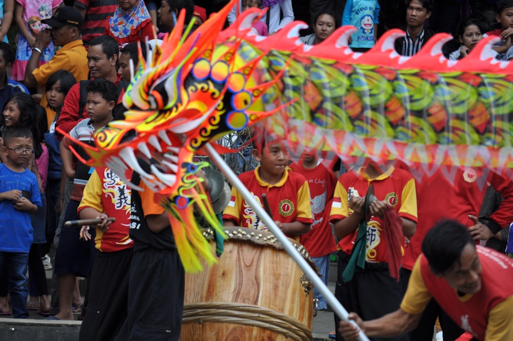 a group of people standing around a drum with a dragon on it