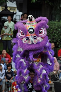 a man in a purple lion costume standing in front of a crowd