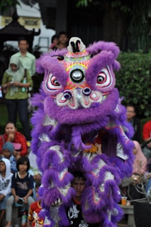a man in a purple lion costume standing in front of a crowd