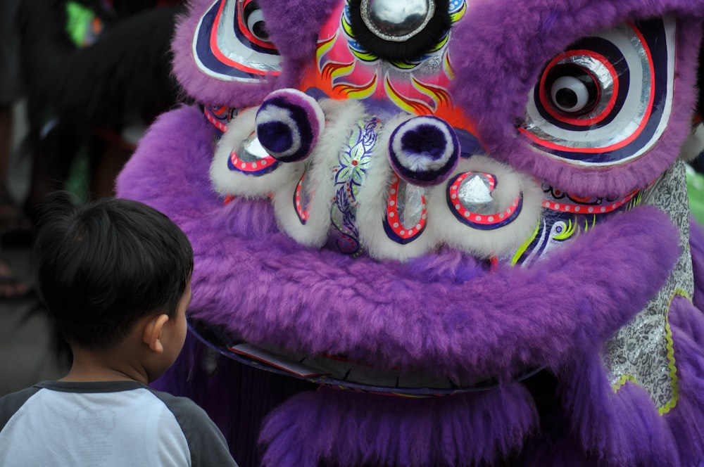 a young boy standing next to a purple dragon