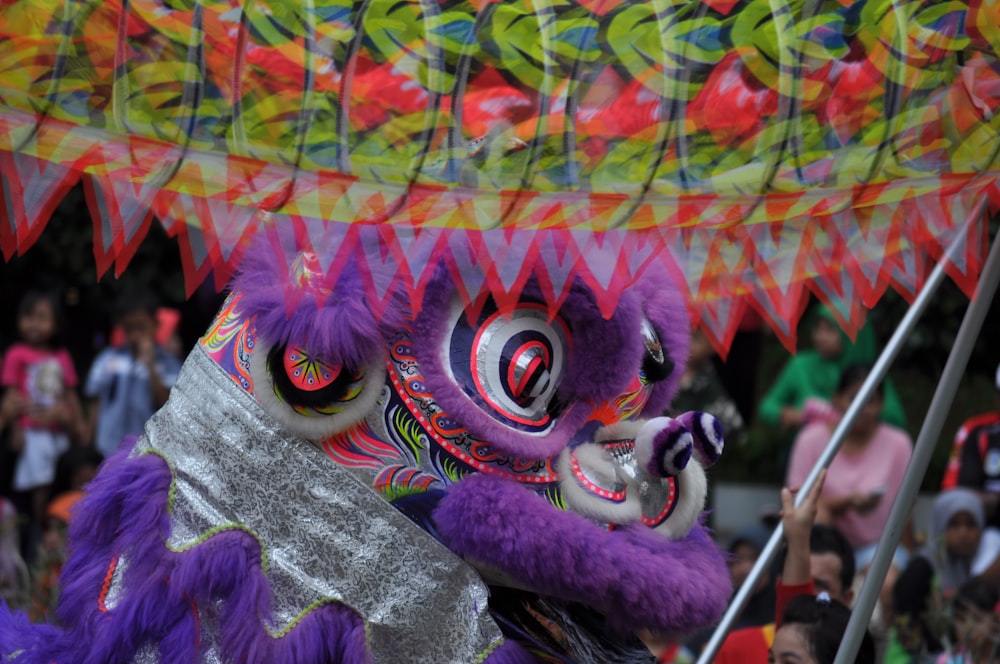 a purple and yellow dragon costume with people in the background