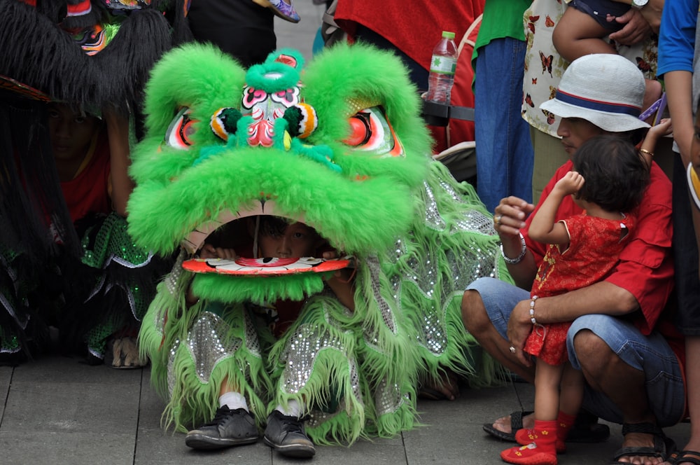 a person in a green dragon costume sitting on the ground
