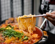 a person holding a spoon full of noodles