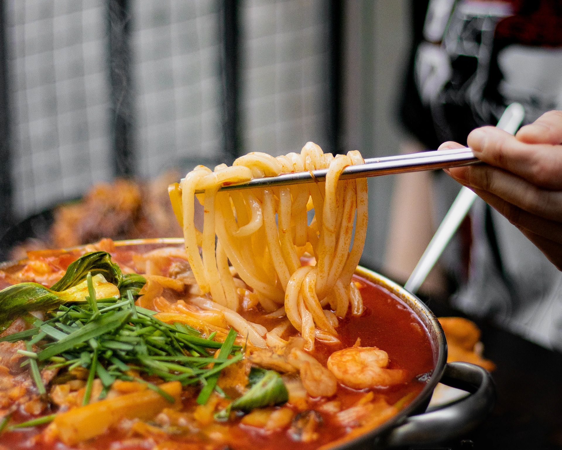 a person holding a spoon full of noodles