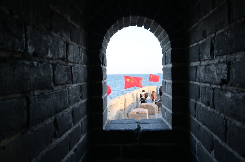 a view of the ocean through a tunnel in a brick wall