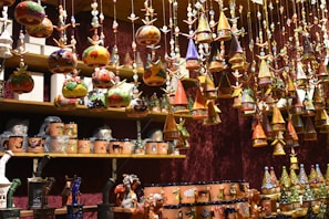 A collection of handmade ceramic ornaments displayed on a rustic wooden shelf, each piece unique in shape and glaze.