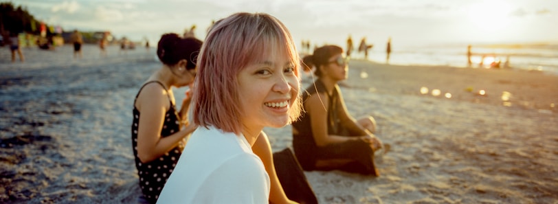 a group of people sitting on top of a sandy beach