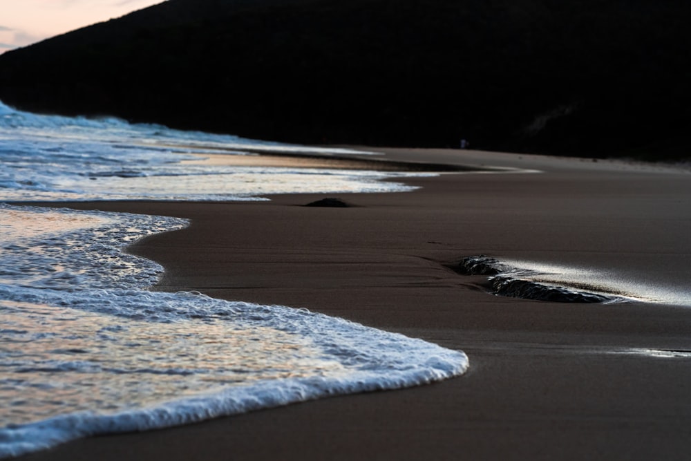 a sandy beach with waves coming in to shore