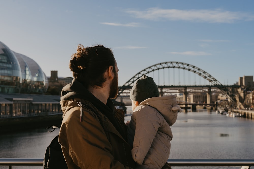 a man holding a child looking at a bridge