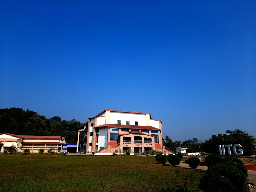 a large white building sitting on top of a lush green field