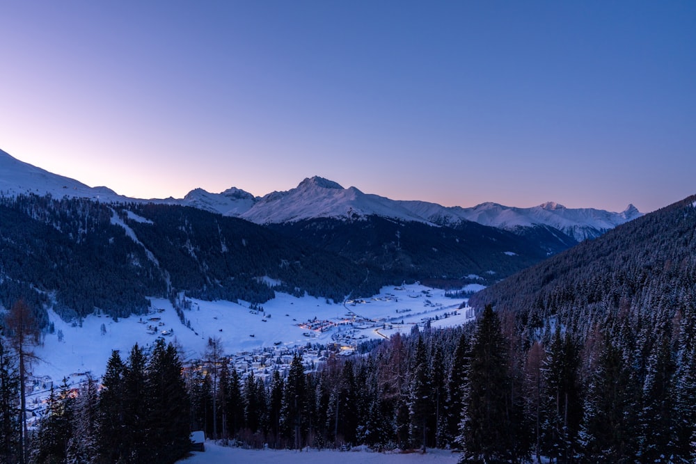 a view of a snowy mountain range at dusk