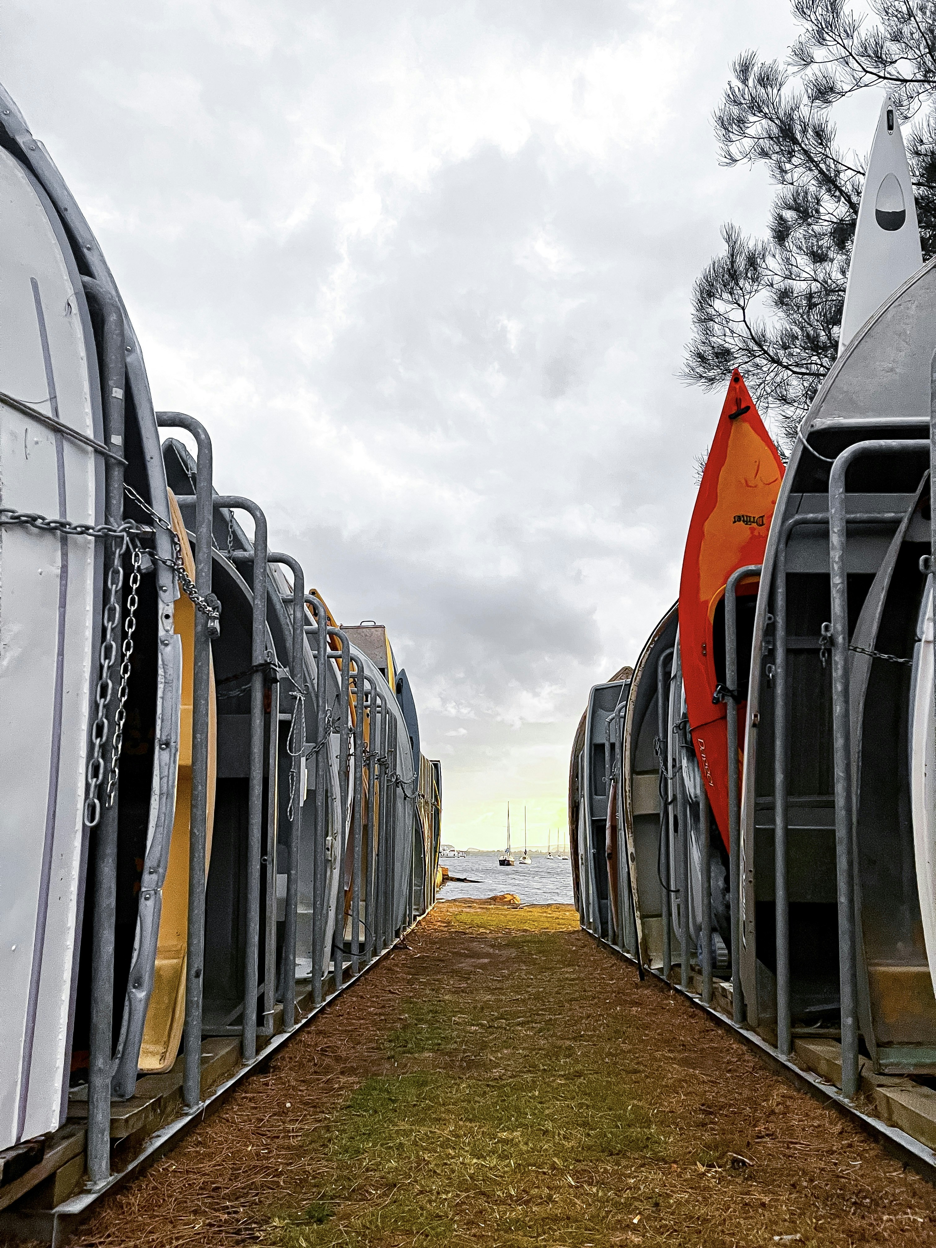 a row of parked boats sitting on top of a grass covered field