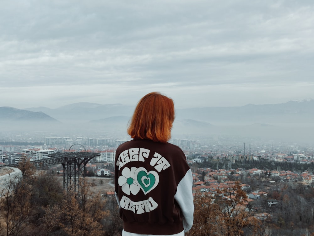 a woman standing on top of a hill overlooking a city