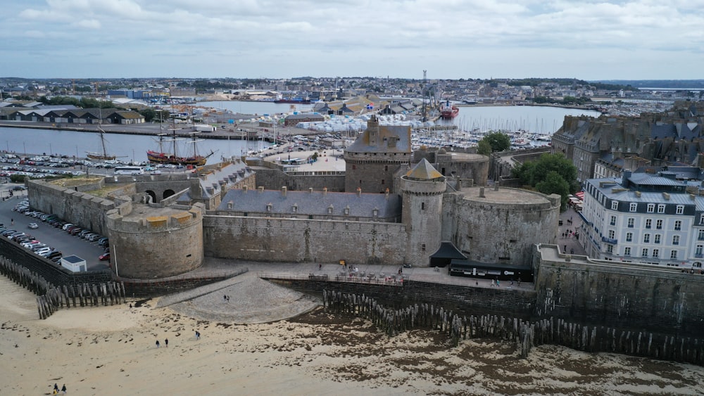 an aerial view of a large castle with a harbor in the background