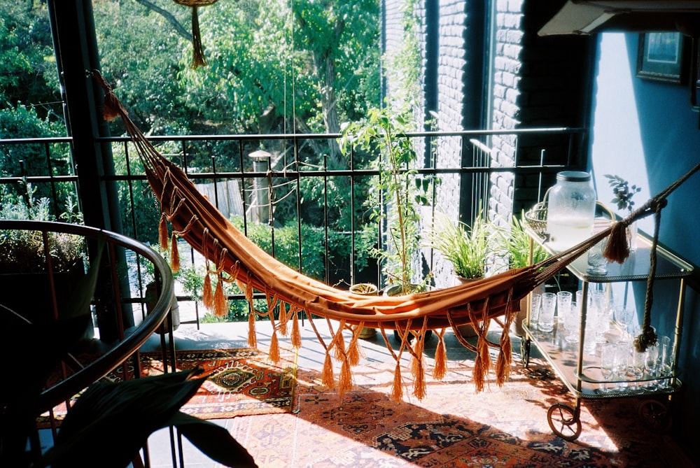 a hammock hanging on a balcony next to a potted plant