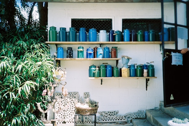 Close-up of colorful personalized potti containers stacked neatly on a wooden shelf.