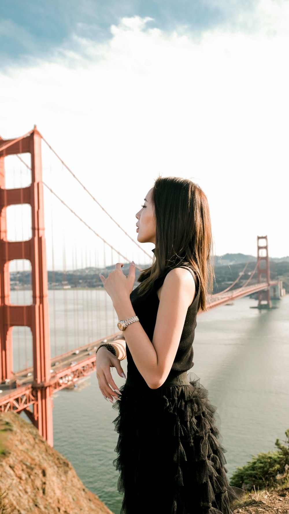 a woman in a black dress standing in front of the golden gate bridge