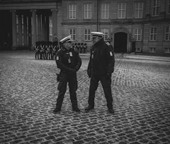 a couple of men standing next to each other in front of a building