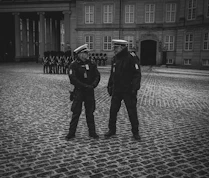 a couple of men standing next to each other in front of a building