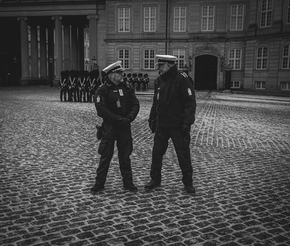 a couple of men standing next to each other in front of a building