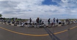 A group of motorbikes lined up on a coastal road with ocean views.