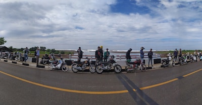 A group of motorbikes lined up on a coastal road with ocean views.