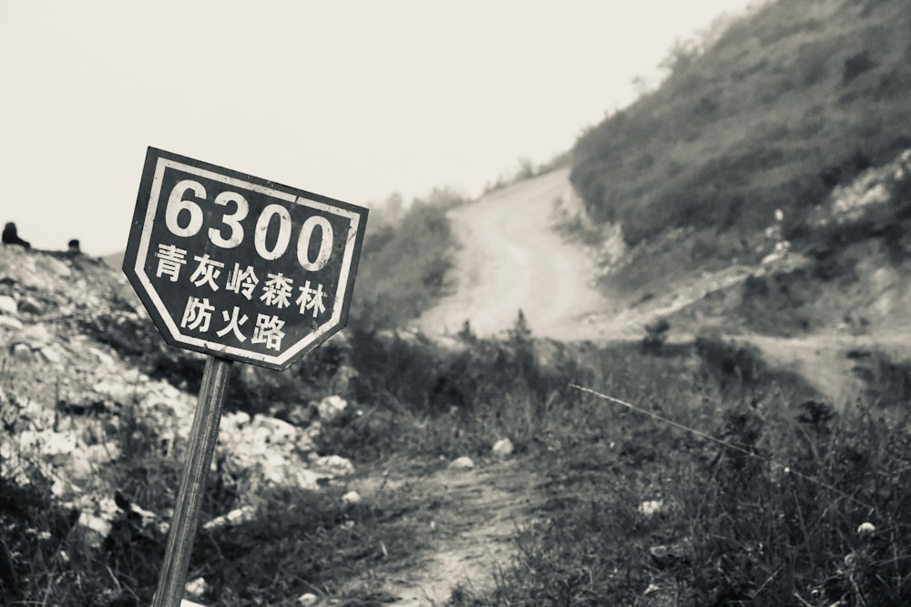 a black and white photo of a sign on a dirt road