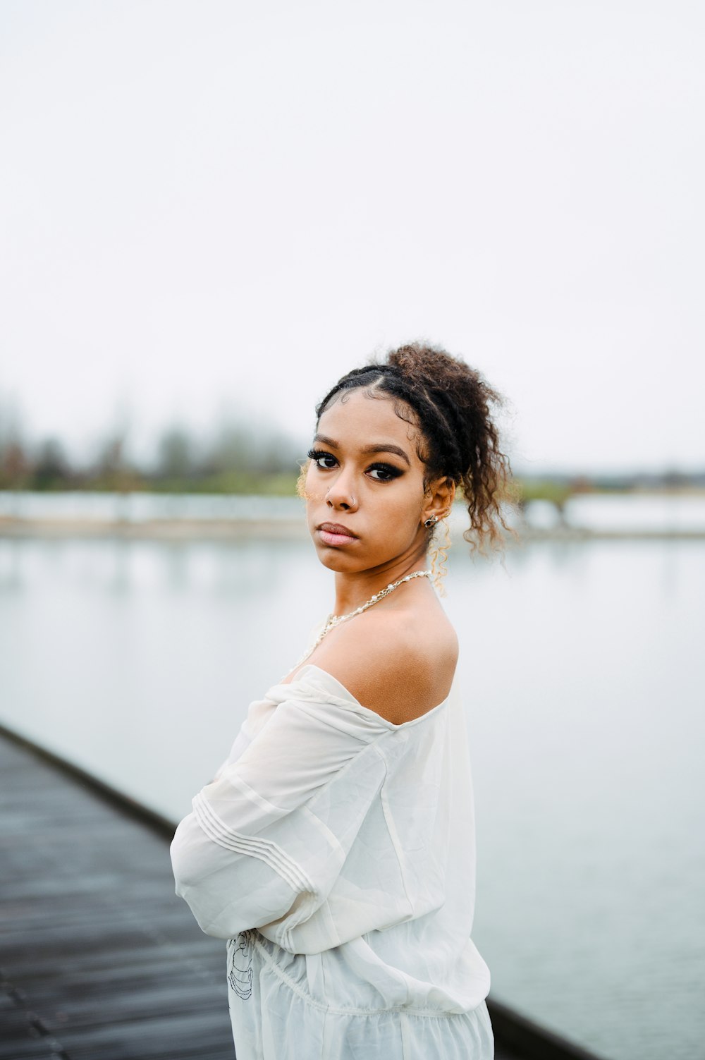 a woman standing on top of a pier next to a body of water