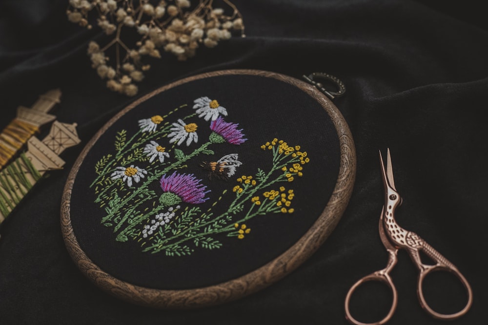 a close up of a embroidery on a black cloth with a pair of scissors