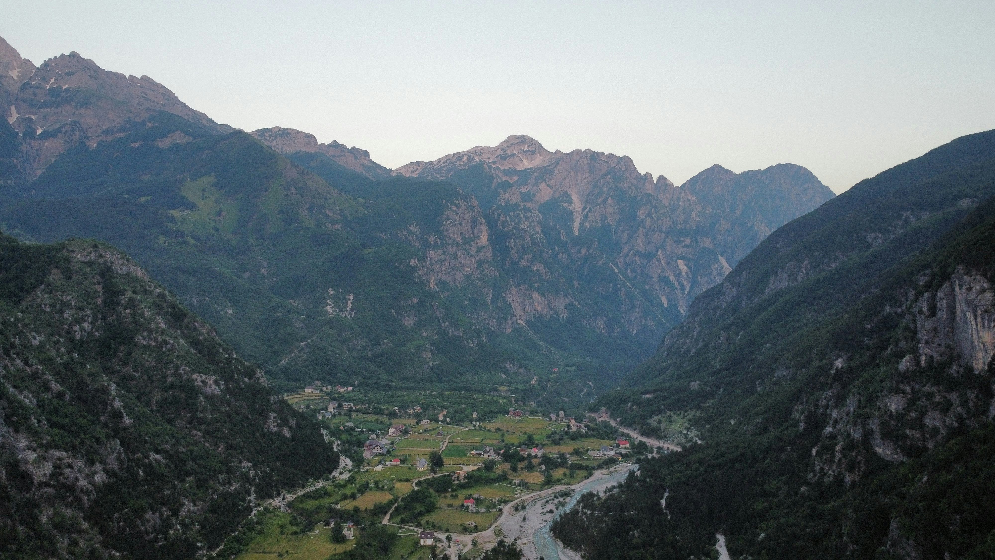 a valley surrounded by mountains with a river running through it