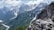 A hiker resting on a rocky outcrop overlooking a vibrant mountain valley.