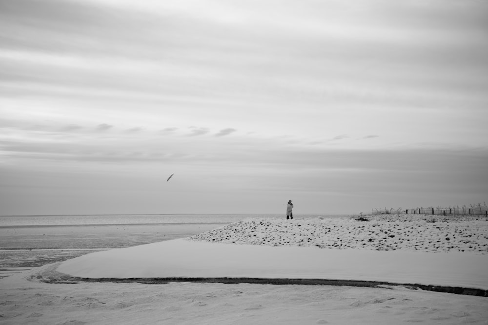 a black and white photo of a person flying a kite