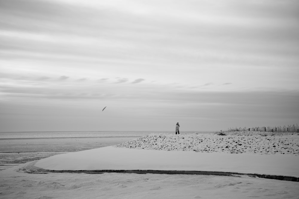 Una foto in bianco e nero di una persona che fa volare un aquilone