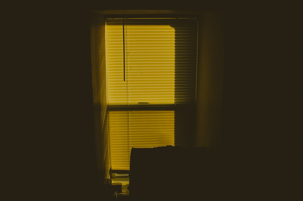 a yellow light shining through a window in a dark room