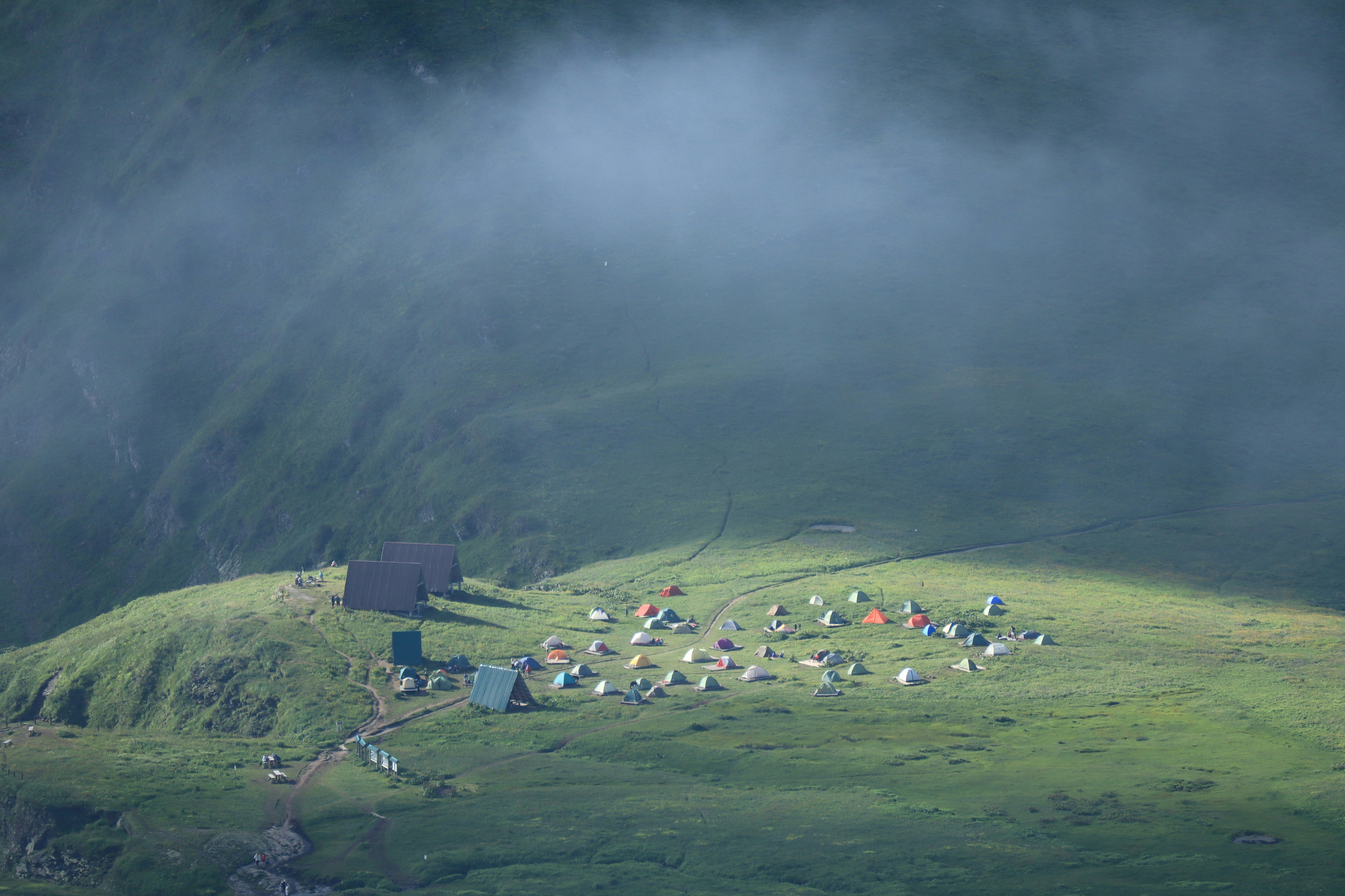 a group of tents set up on a grassy hill