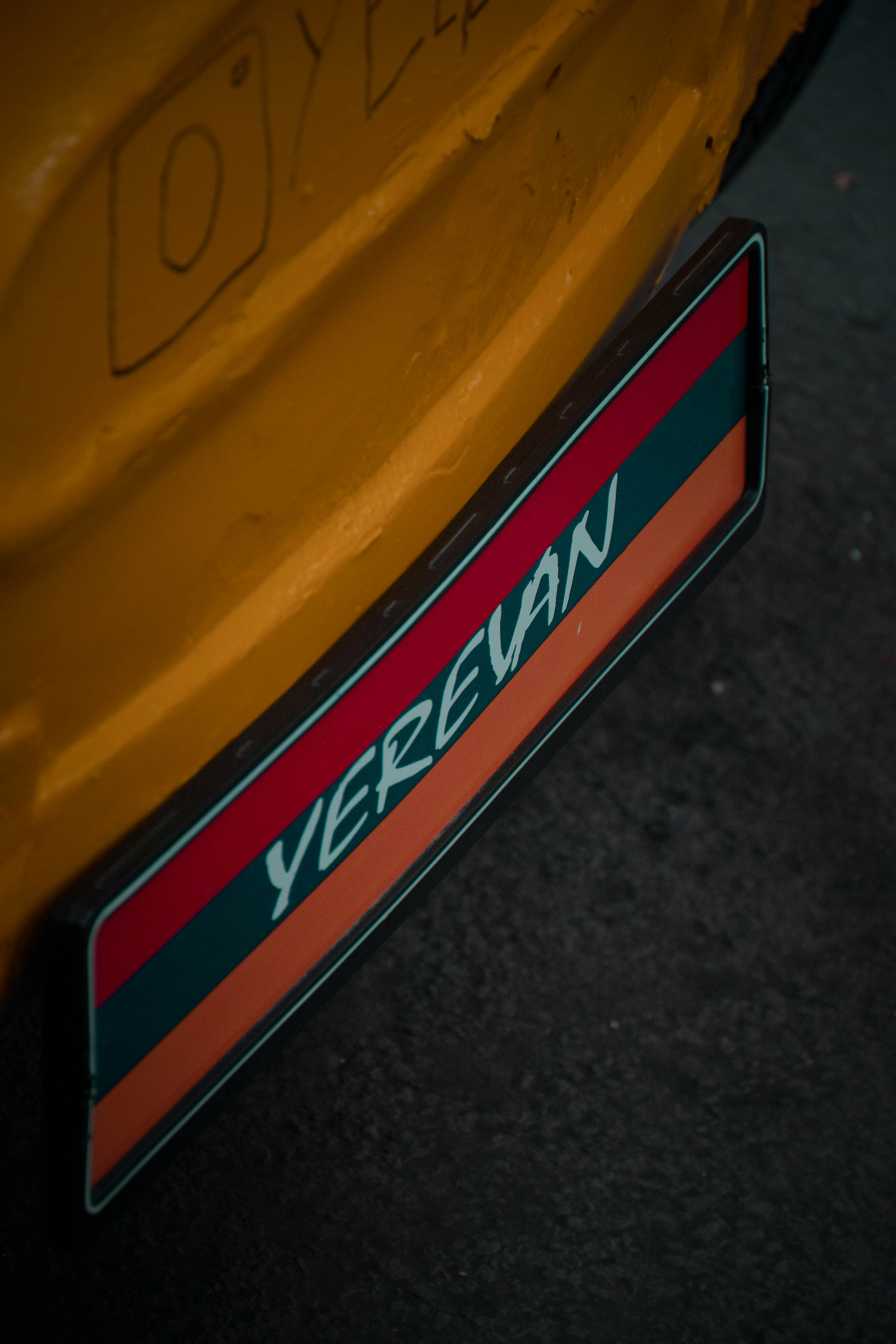 Un primo piano di un'auto gialla con una striscia rossa e verde