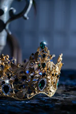 Close-up of a delicate crown resting on a vintage velvet cushion with soft golden light.