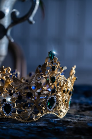 Close-up of a detailed medieval crown resting on a velvet cushion.